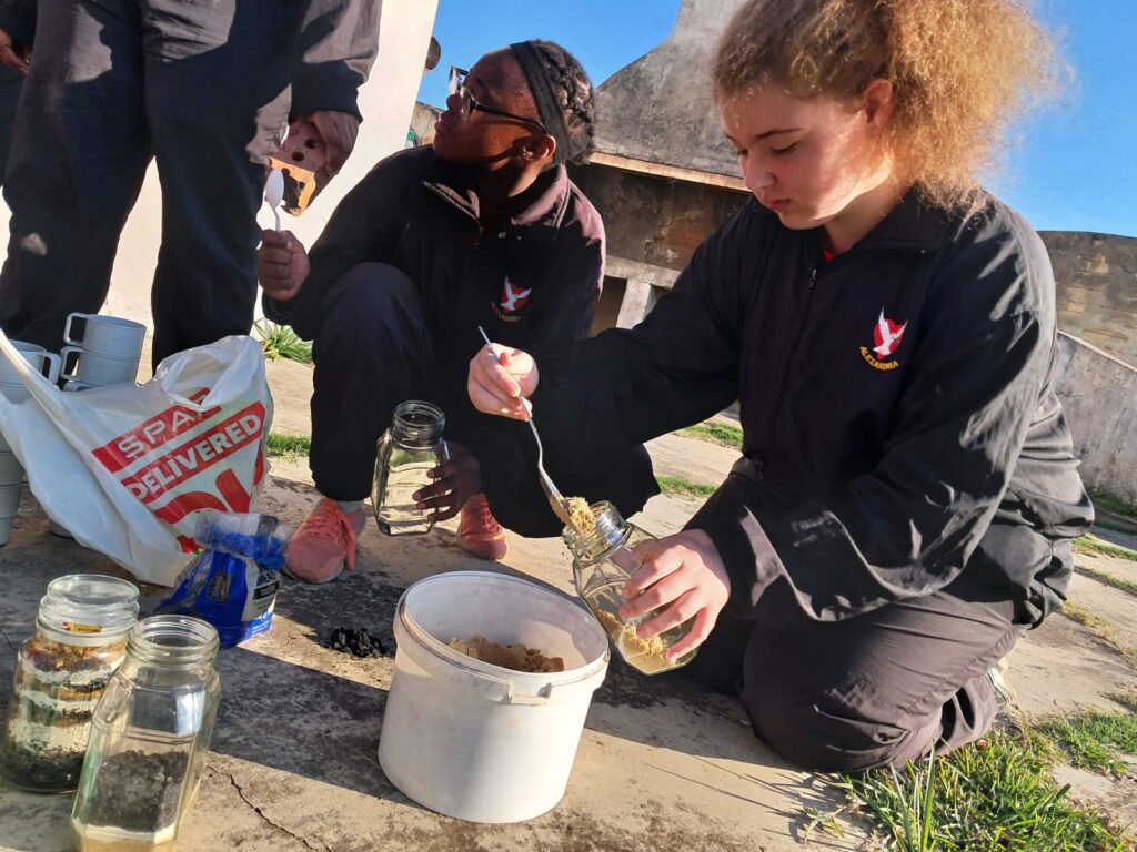 Grade 7–9 learners created colourful soil profile layers using different types of soil.