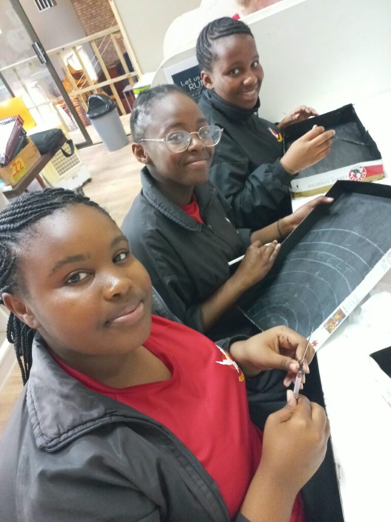 Enzokuhle Maqwili, Alive Singqoto and Emihle Harmans proudly displaying their solar system project.