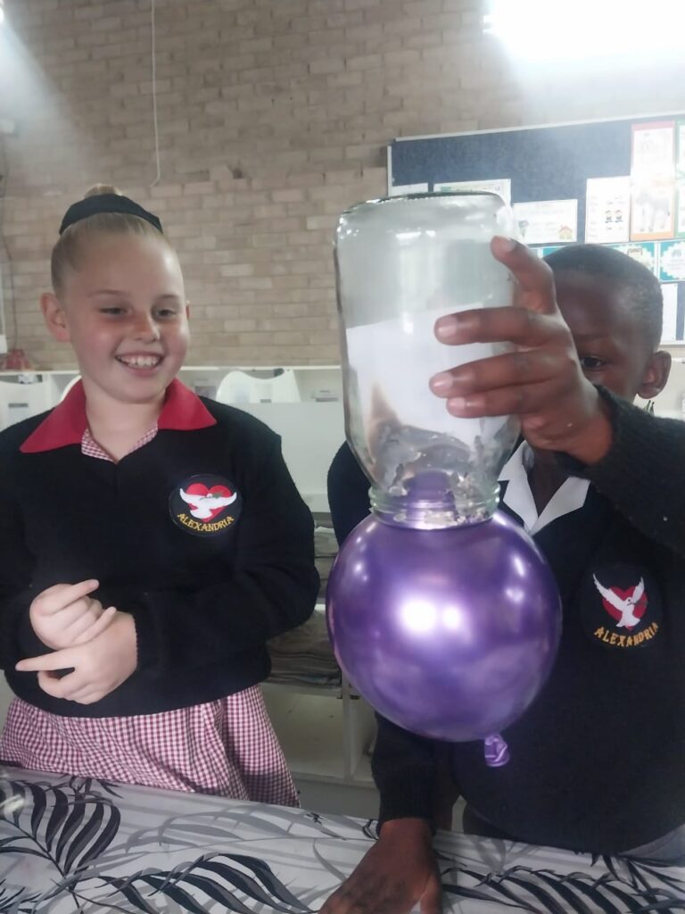 Tatum Bernard and Silubonile Magobiyane observe a science experiment as part of their classroom learning.